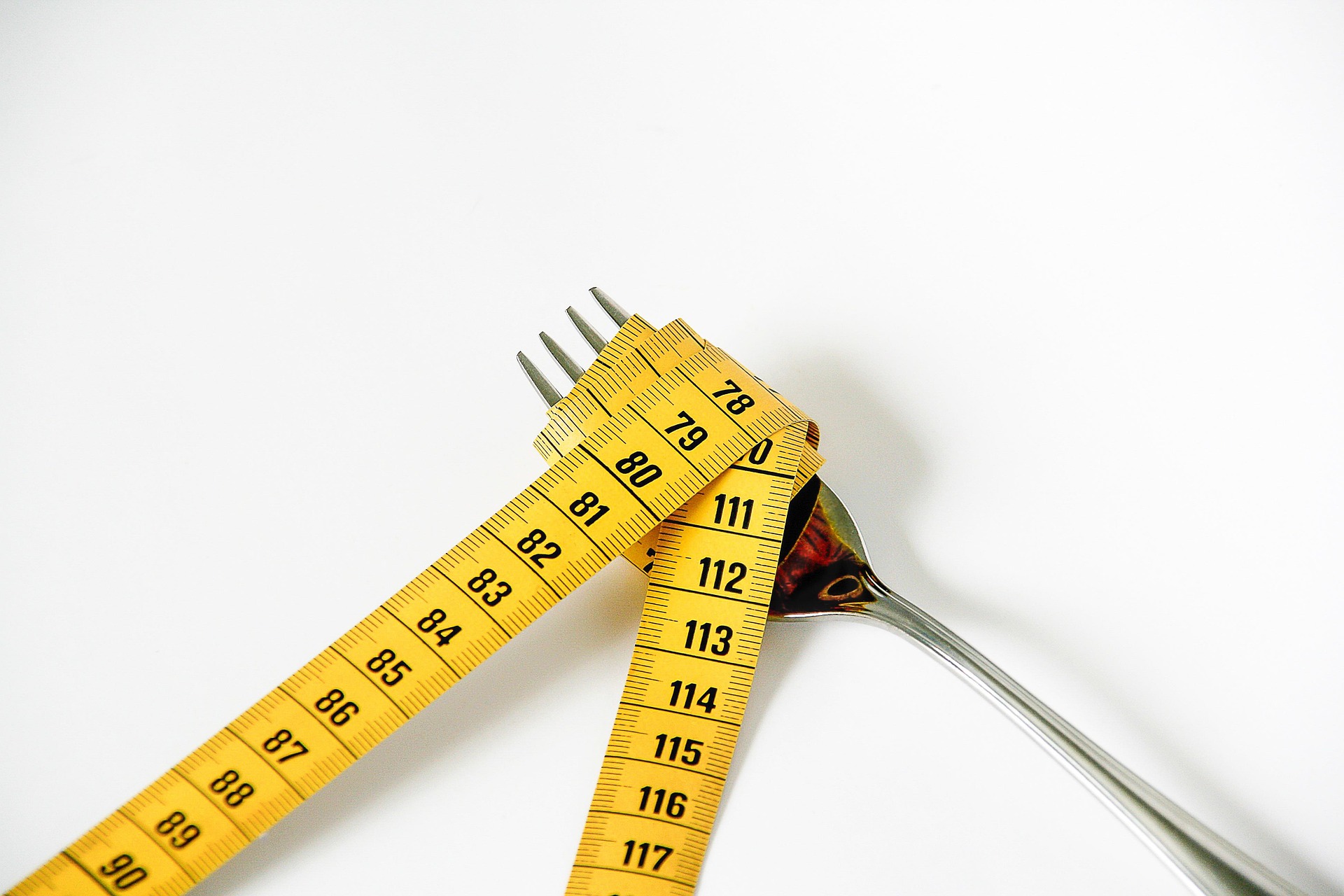 Cinta métrica alrededor de un tenedor como representación de la relación entre alimentación, peso y cuerpo